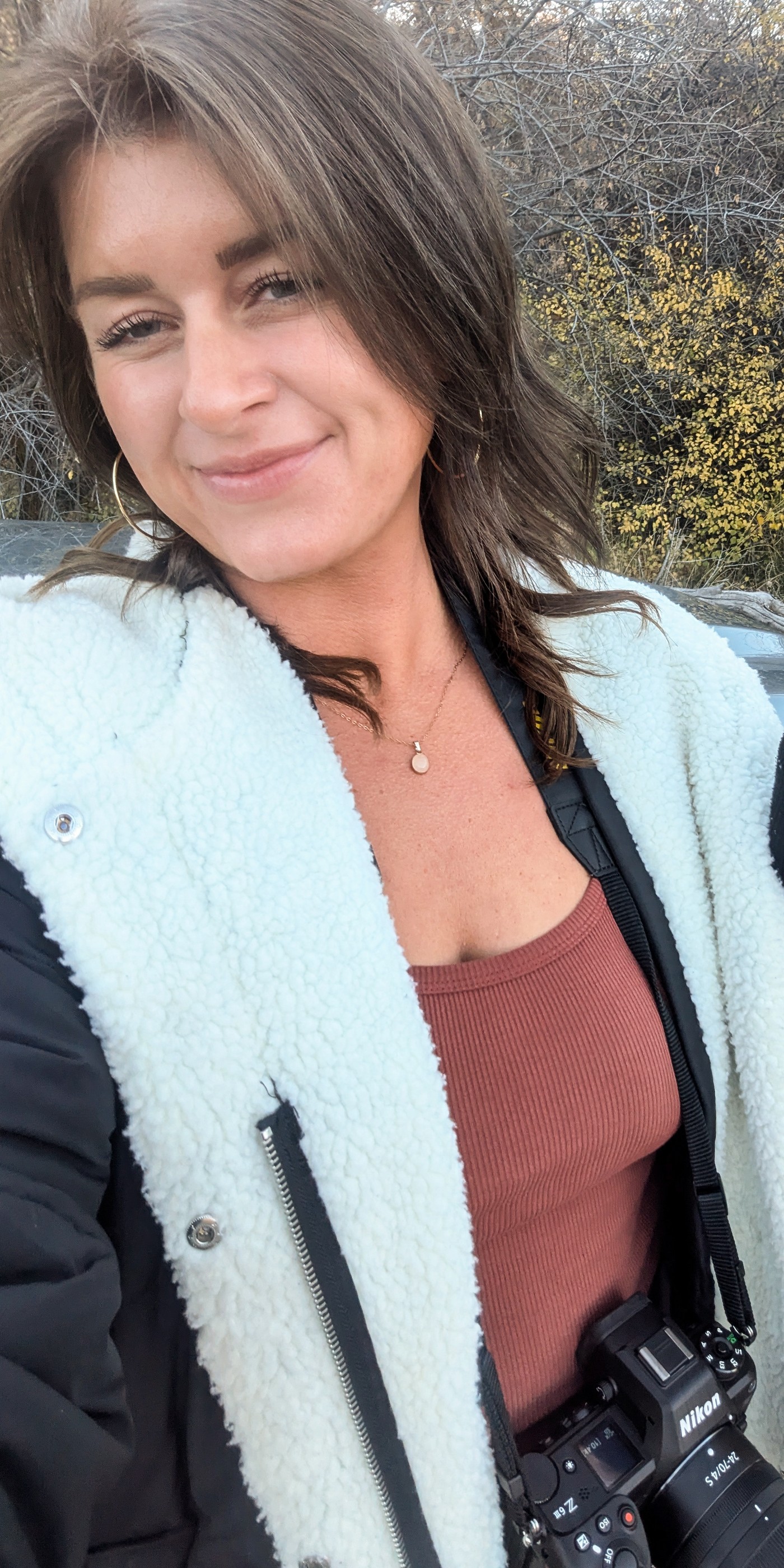 Jen Kunz smiling outdoors with a camera