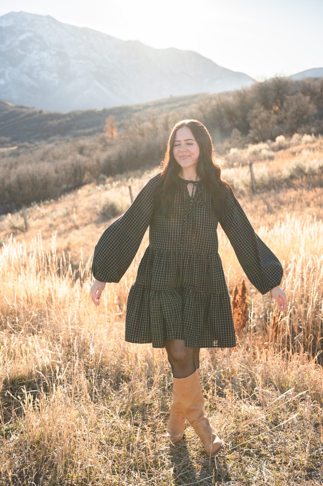 Young woman in a black dress standing in a sunlit field