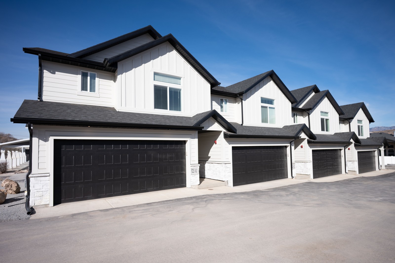 White townhomes with black garage doors under a blue sky
